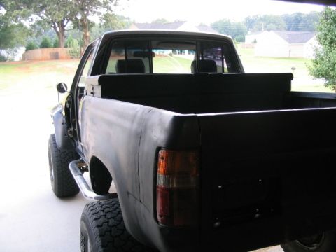 1986 Ford F-150 - Rear view of a black pickup truck with custom fender flares and off-road tires.