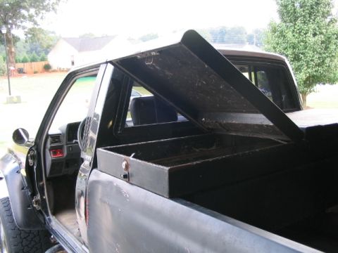1986 Ford F-150 - The interior and bed of a pickup truck are visible, an open toolbox.