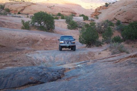 1996 Ford Bronco - 1996 Ford Bronco navigates a challenging off-road path in a desert landscape.