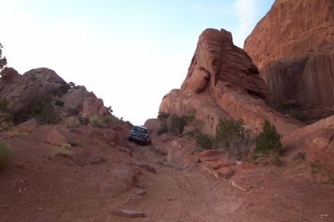 1996 Ford Bronco - 1996 Ford Bronco climbing a challenging off-road path in a desert landscape.