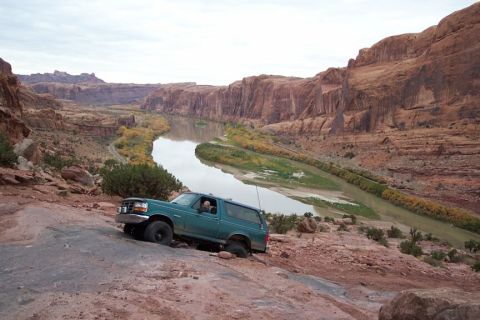 1996 Ford Bronco - A green Ford Bronco navigates a rough trail in a desert canyon landscape.