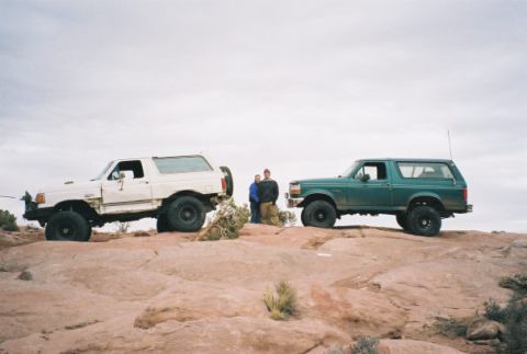 1996 Ford Bronco - Two Ford Broncos are parked on a rocky outcrop under an overcast sky.