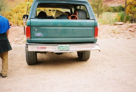 1996 Ford Bronco - The rear of a green Ford Bronco is shown, with a spare tire and other items in the cargo area.