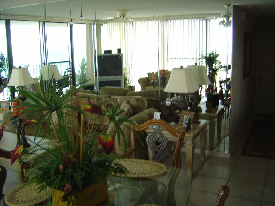 Interior scene with sofas, lamps, plants, and mirrored walls