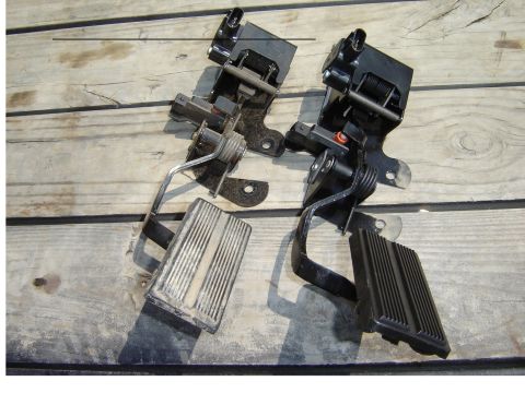 1992 Ford Bronco - Two brake and gas pedal assemblies are shown, likely for a vehicle, resting on a wooden background.