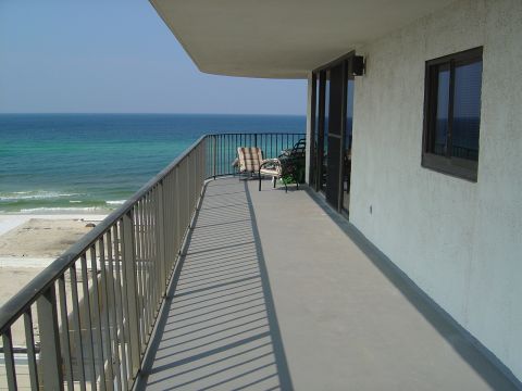 1986 Ford Bronco - A balcony with a railing offers a view of the ocean and beach on a sunny day.