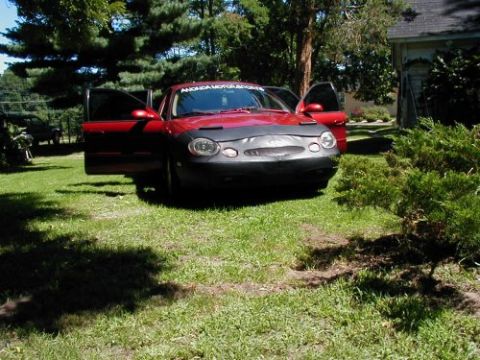 1997 Ford Taurus - A red sedan with its doors ajar sits on a lawn, partially obscured by a black car bra.