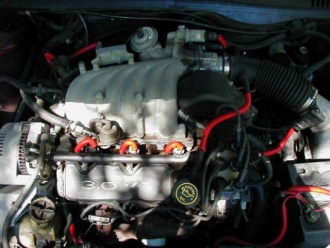 1997 Ford Taurus - Close-up of a 1997 Ford Taurus engine, showing the 3.0L V6 configuration and red spark plug wires.