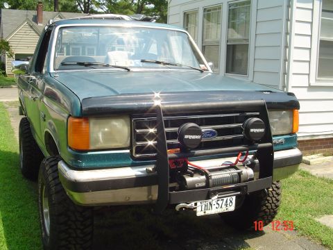 1989 Ford Bronco - 1989 Ford Bronco equipped with a winch and brush guard, parked outdoors.