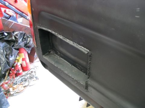 1986 Ford F-150 - A close-up view of a modified black panel on a vehicle, revealing internal metalwork and surrounding items.