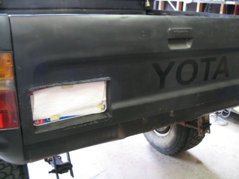 1986 Ford F-150 - Rear view of a black pickup truck's tailgate, showing the 'YOTA' emblem and a covered license plate opening.