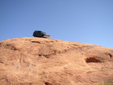 1996 Ford Bronco - A 1992 Ford Bronco is parked on a large rock formation, with a clear blue sky above.
