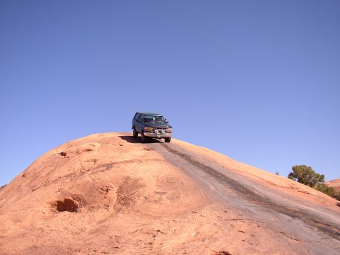 1996 Ford Bronco - Ford Bronco navigates a challenging off-road trail on a large rock formation.