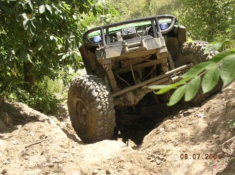 1992 Ford Bronco - An off-road vehicle navigates a steep dirt incline, its front end angled upwards.