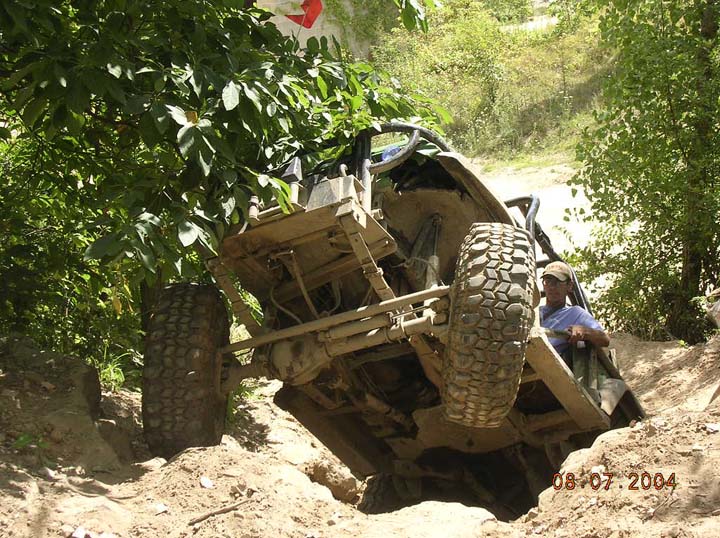 Off-road vehicle tilted on a dirt trail with a person inside