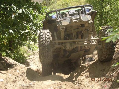 1992 Ford Bronco - An off-road vehicle navigates a challenging dirt path, tilted precariously on its side.