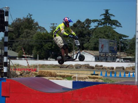 1990 Ford Bronco - A rider soars through the air on a scooter during an event, with a number plate reading '884'.