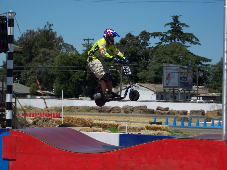 Person on scooter airborne over ramp, number 884 visible
