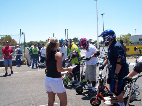1990 Ford Bronco - Participants and organizers gather at the start line for a mini scooter race event.