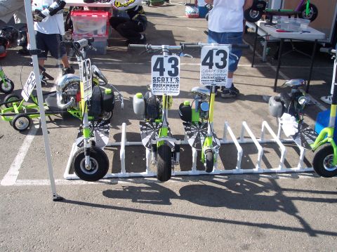 1990 Ford Bronco - Multiple mini scooters are lined up in a rack at an outdoor event.
