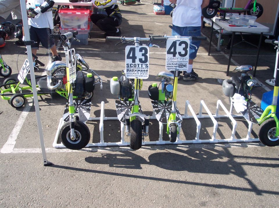 Several green and white mini scooters parked in a white rack