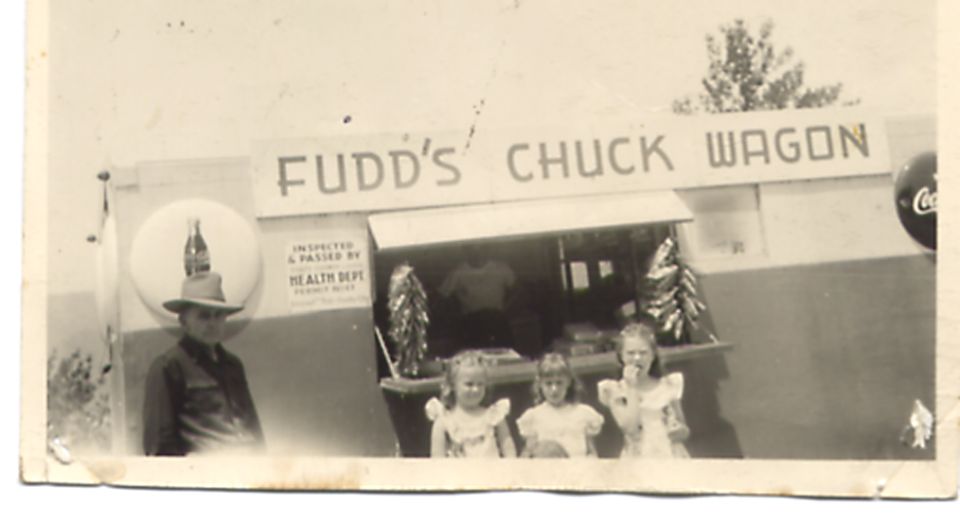 Man in hat stands by Fudd's Chuck Wagon with children in front