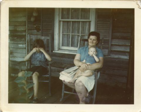 1995 Ford Bronco - A woman and two children relax on a wooden porch in rocking chairs.