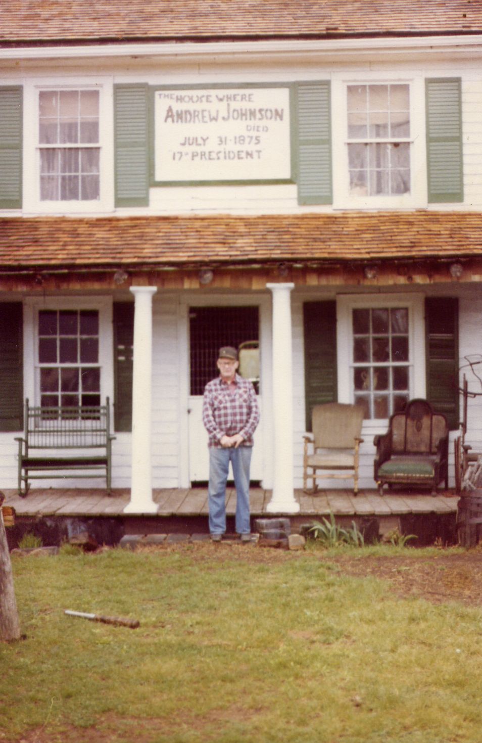 House with sign 'The house where Andrew Johnson died July 31, 1975 17th President'. Man in plaid shirt stands on porch