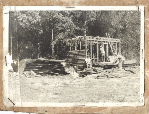 1995 Ford Bronco - Workers are actively engaged in building a wooden structure, with lumber and materials scattered around the site.