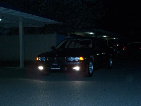 1999 BMW 7 Series - A black 1999 BMW 7 Series sedan is seen from the front at night, with its headlights illuminated.