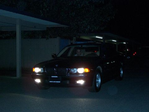 1999 BMW 7 Series - A black 1999 BMW 7 Series sedan is seen from the front at night, with its headlights illuminated.