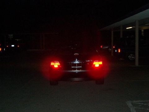 1999 BMW 7 Series - The rear of a sedan is visible at night, with its brake lights illuminated.