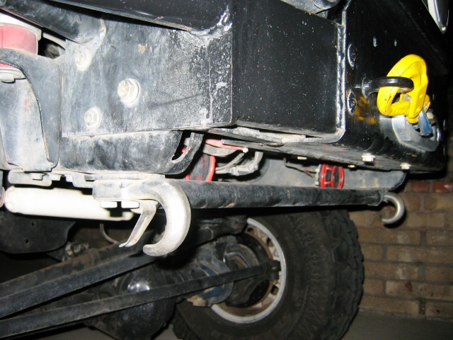Underside of black truck showing chrome tow hook, frame, and yellow tow loop