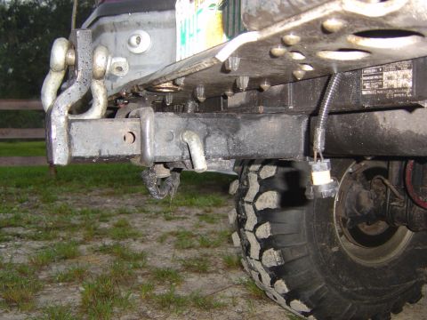 1993 Ford Bronco - Close-up of a vehicle's rear bumper, tow hitch, and tire with off-road tread.