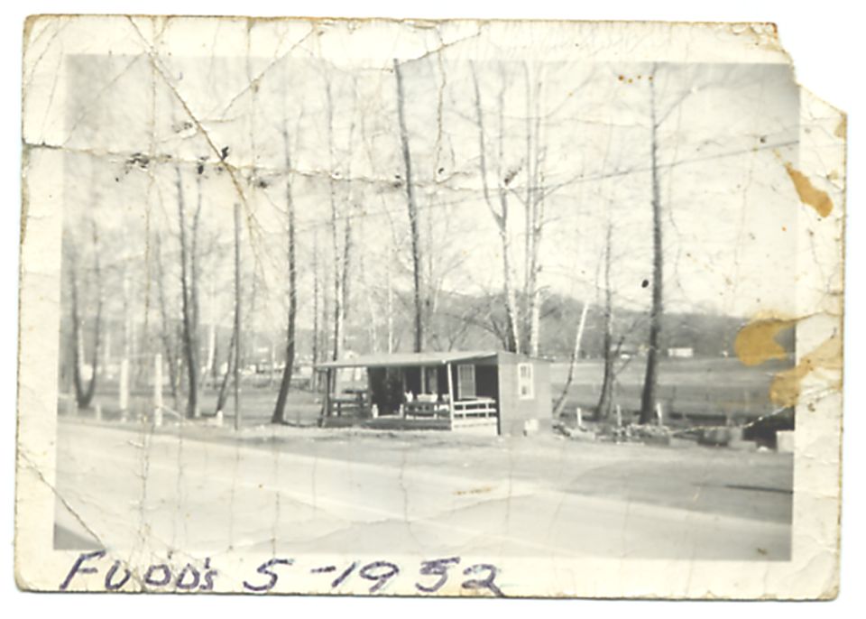 Handwritten text "Food's 5-1952" on a vintage photo of a small building and trees