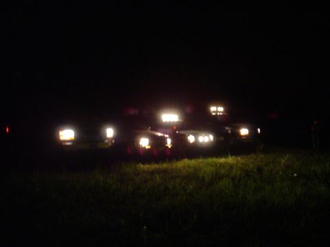 1993 Ford Bronco - Multiple vehicles are gathered at night, illuminated by their own lights.