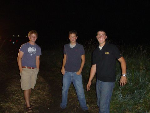 1993 Ford Bronco - Three men are standing in a field at night, with some lights in the background.