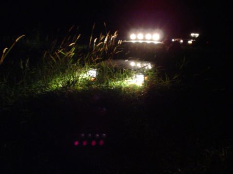 1993 Ford Bronco - Two vehicles are seen off-roading at night, illuminated by their headlights and auxiliary lights.