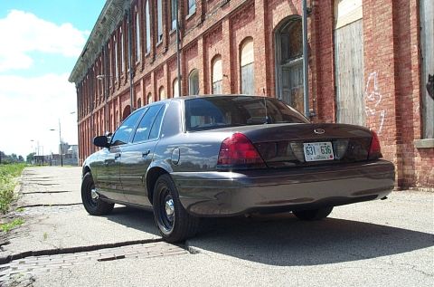 2001 Ford Crown Victoria - A 2001 Ford Crown Victoria is seen from the rear, parked in front of a brick building.