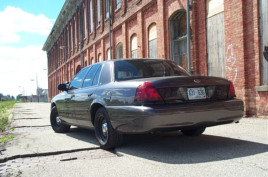 Dark gray 2001 Ford Crown Victoria parked on cracked pavement, rear view
