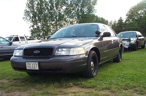 2001 Ford Crown Victoria - A 2001 Ford Crown Victoria Police Interceptor is parked on grass, with another similar vehicle behind it.