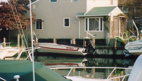 1994 Ford Bronco - A boat is docked next to a house on a canal, with other boats visible.