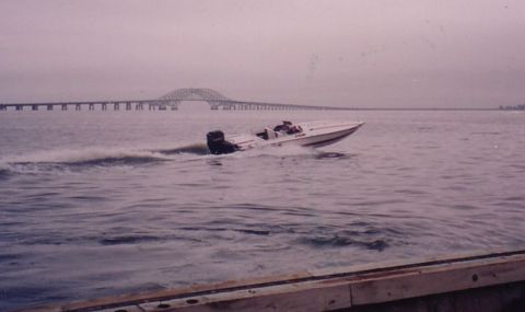 1994 Ford Bronco - A white speed boat cuts through the water with a long bridge spanning the horizon.