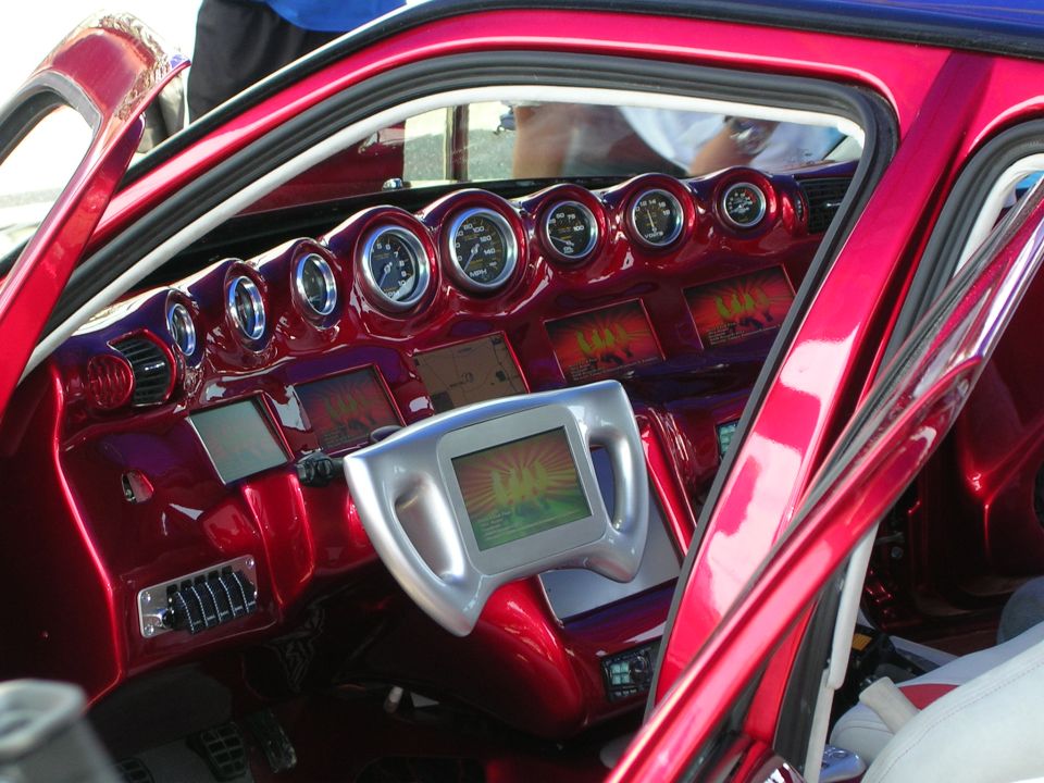Custom car interior with red dashboard, multiple gauges, and a central screen