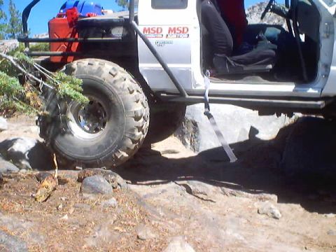 1976 Ford F-100 - Off-road truck navigating rocky terrain with large tires and external fuel cans.