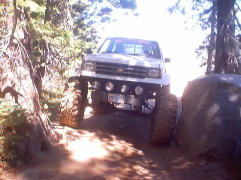 1976 Ford F-100 - This modified pickup truck navigates a rocky off-road trail through a wooded area.