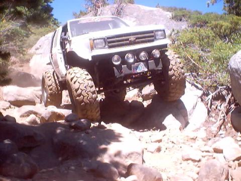 1976 Ford F-100 - This modified vehicle navigates a challenging rocky terrain under a clear blue sky.