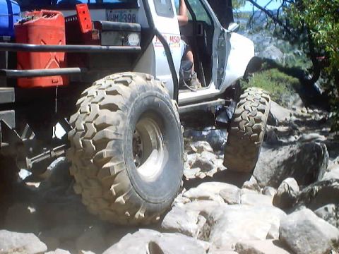 1976 Ford F-100 - A modified off-road vehicle tackles a challenging rocky trail with its large tires.