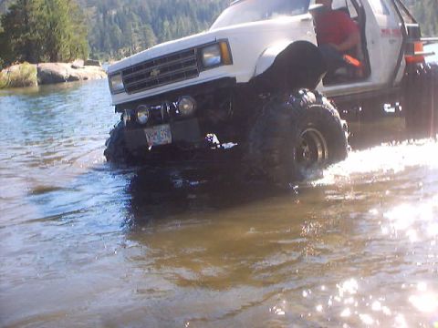 1976 Ford F-100 - A modified pickup truck navigates through a body of water, its large tires splashing.