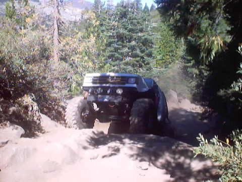 1976 Ford F-100 - An off-road vehicle navigates a dusty, rocky path through a wooded area.